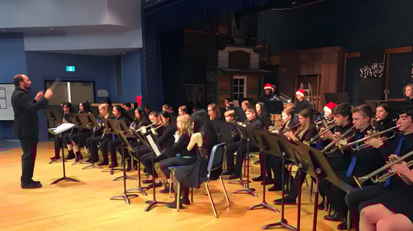 Eine Gruppe von Musikschülern der Parkland Secondary School spielt unter der Leitung eines Dirigenten auf der Bühne.