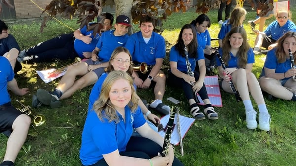 Eine Gruppe Schülerinnen und Schüler der Pasadena Academy steht draußen auf einer Wiese vor Bäumen.