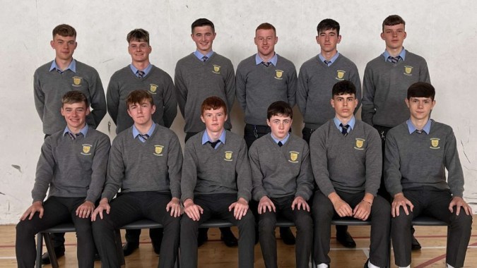 Eine Gruppe von Schülern der Patrician High School in Schuluniformen posiert vor einer schlichten Wand für ein Gruppenfoto.