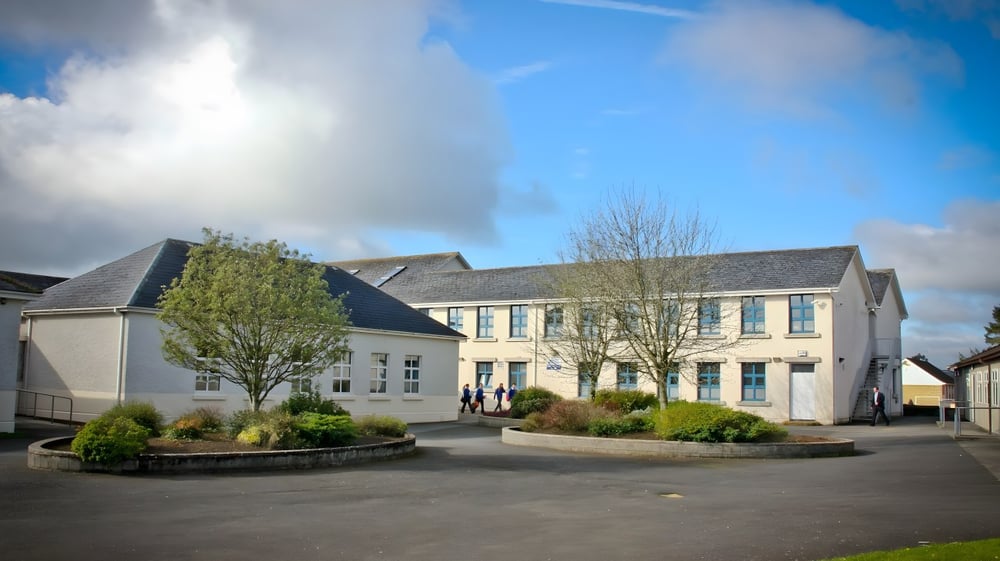 Das mehrstöckige Gebäude der Patrician Presentation Secondary School mit einem Innenhof und angelegten Grünflächen unter bewölktem Himmel.