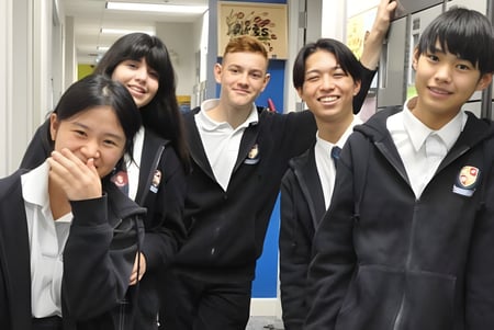 Eine Gruppe Schüler in Schuluniformen steht im Flur der Pattison High School vor verschiedenen Schuldekorationen.