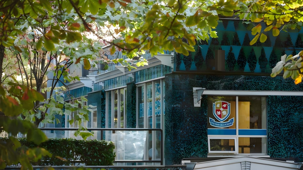 Das Gebäude mit Glasfassade auf dem Campus der Pattison High School ist umgeben von üppigem Grün.