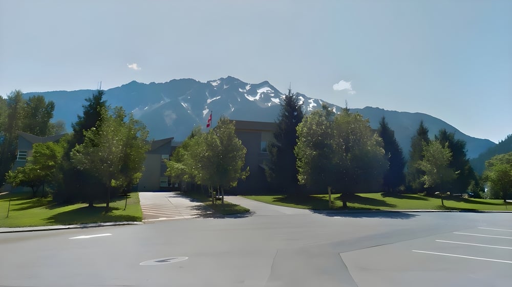 Ein gepflasterter Weg führt durch eine grüne Landschaft zu den Bergen auf dem Gelände der Pemberton Secondary School.