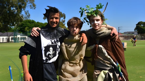 Drei Personen im Kostüm stehen auf einer Wiese auf dem Gelände der Pembroke School.