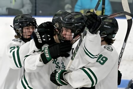 Eine Gruppe Schüler in weißen und grünen Trikots spielt Hockey auf der Eisbahn der Pender Harbour Secondary.