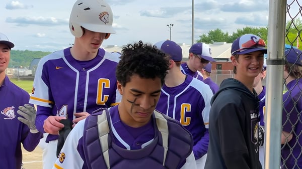 Eine Gruppe junger Baseballspieler in lila Uniformen steht auf dem Baseballfeld der Peoria Christian School.