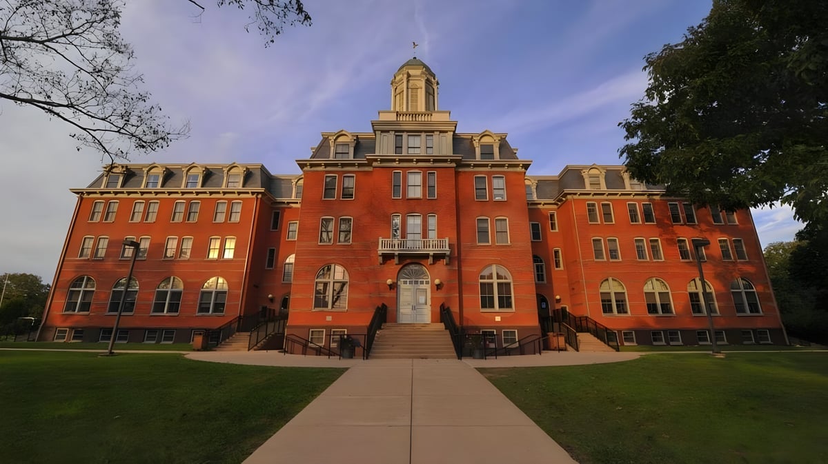 Das rote Backsteingebäude der Perkiomen School steht auf einer gepflegten Rasenfläche mit Bäumen im Hintergrund.