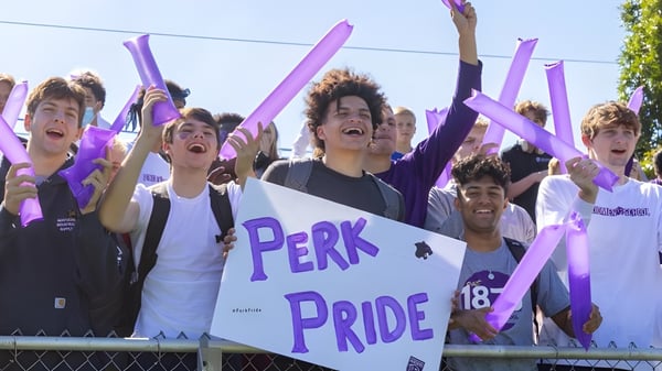 Eine Gruppe von Schülern der Perkiomen School hält lila Fahnen und Schilder bei einer Pride-Feier im Freien.