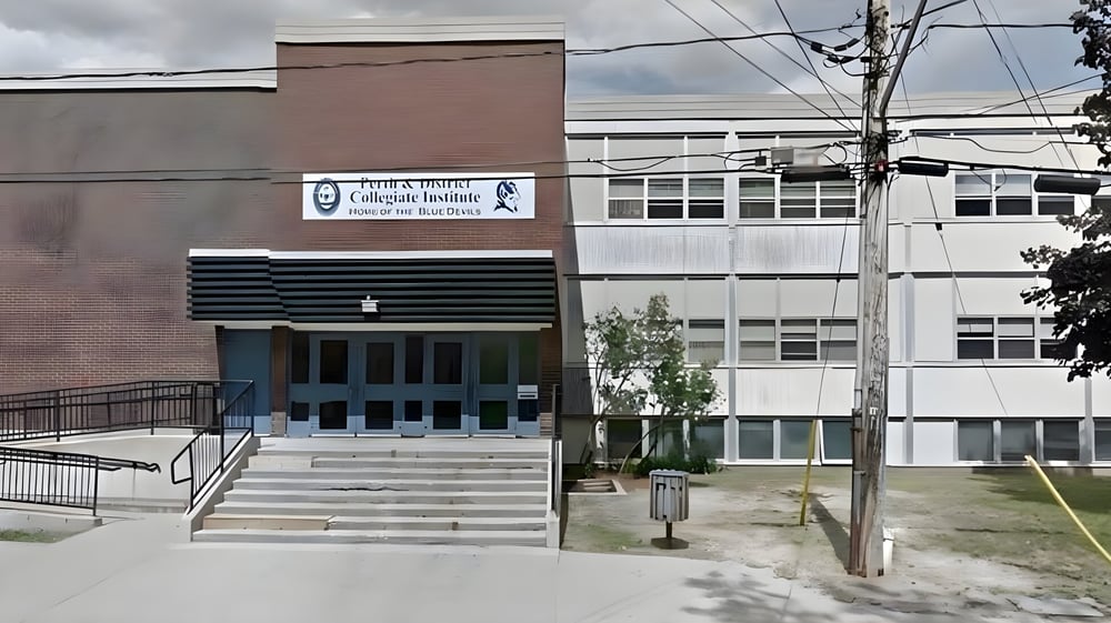 Das mehrstöckige Hauptgebäude des Perth & District Collegiate Institute mit Stufen und Stromleitungen im Vordergrund.