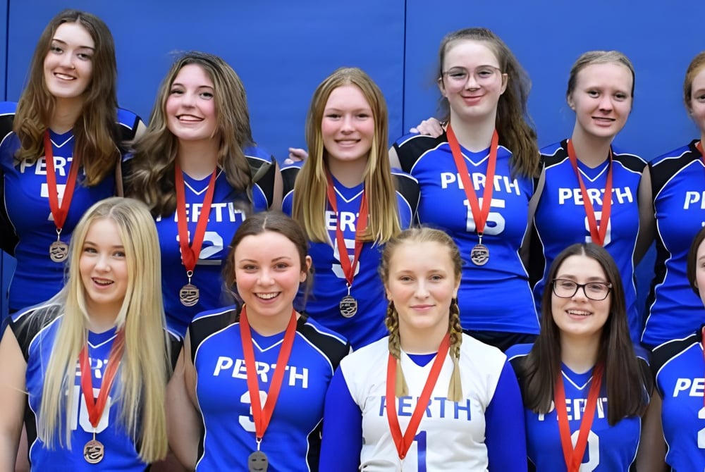 Eine Gruppe von Schülerinnen des Perth & District Collegiate Institute trägt blaue Uniformen und zeigt ihre Medaillen vor blauem Hintergrund.