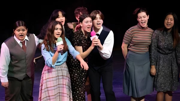 Schüler der Phillips Academy stehen gemeinsam auf der Bühne und führen einen Auftritt vor dunklem Hintergrund aus.