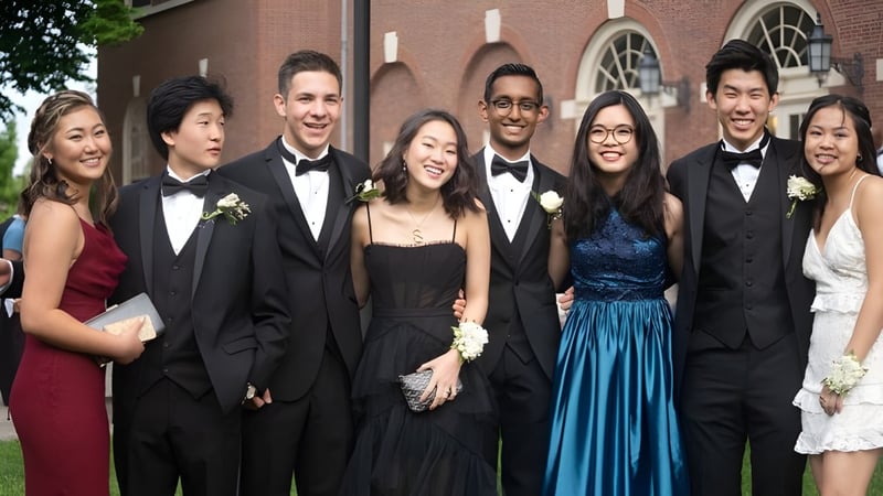 Eine Gruppe von Schülerinnen und Schülern der Phillips Academy posiert in formeller Kleidung vor einem Backsteingebäude mit Rundbogenfenstern bei einer Veranstaltung.