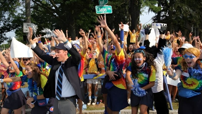Eine große Gruppe Schülerinnen und Schüler der Phillips Academy versammelt sich draußen mit erhobenen Armen.
