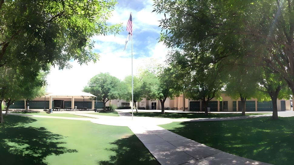 Der Campus der Phoenix Christian Preparatory School zeigt einen baumgesäumten Weg mit einem Gebäude und der amerikanischen Flagge.