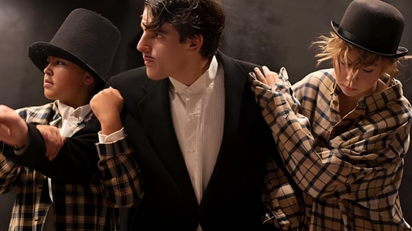 Drei Personen, darunter zwei Männer und eine Frau, stehen zusammen in einem schwach beleuchteten Raum auf dem Campus der Phoenix Christian Preparatory School.