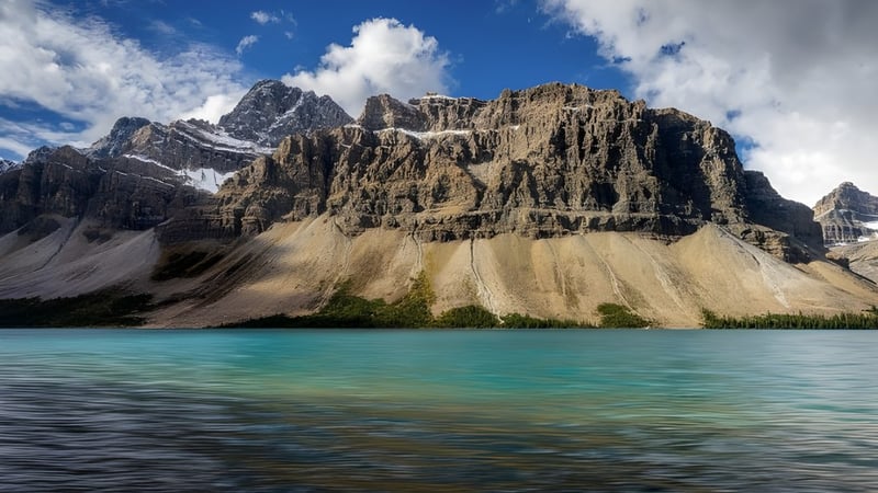 Blick auf schneebedeckte Berge und einen türkisfarbenen See nahe der Picture Butte High School.