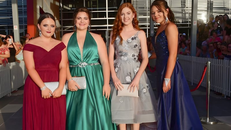 Vier Schülerinnen der Pimlico State High School posieren gemeinsam in Abendkleidern auf einem roten Teppich.