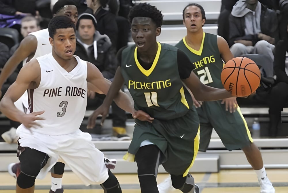 Zwei Basketballspieler kämpfen um den Ball auf dem Spielfeld der Pine Ridge Secondary School vor Zuschauern.