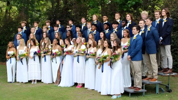 Eine Gruppe von Schülern der Pinewood Preparatory School steht gemeinsam in formeller Kleidung in einer grünen Außenanlage.