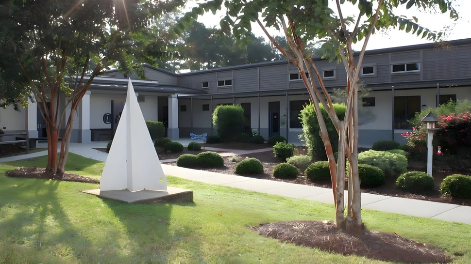 Das moderne zweistöckige Gebäude mit weißer Dreieckskonstruktion liegt auf dem gepflegten Campus der Pinewood Preparatory School.