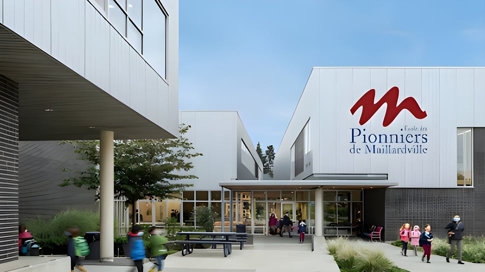 Das moderne Glasgebäude der Pioneer School Port Coquitlam mit dem M-Logo zeigt Menschen auf dem Gehweg davor.