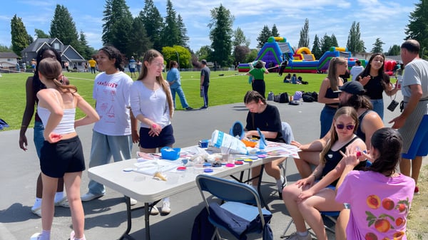 Schüler der Pioneer School Port Coquitlam versammeln sich bei einer Veranstaltung im Park mit aufblasbaren Strukturen im Hintergrund.