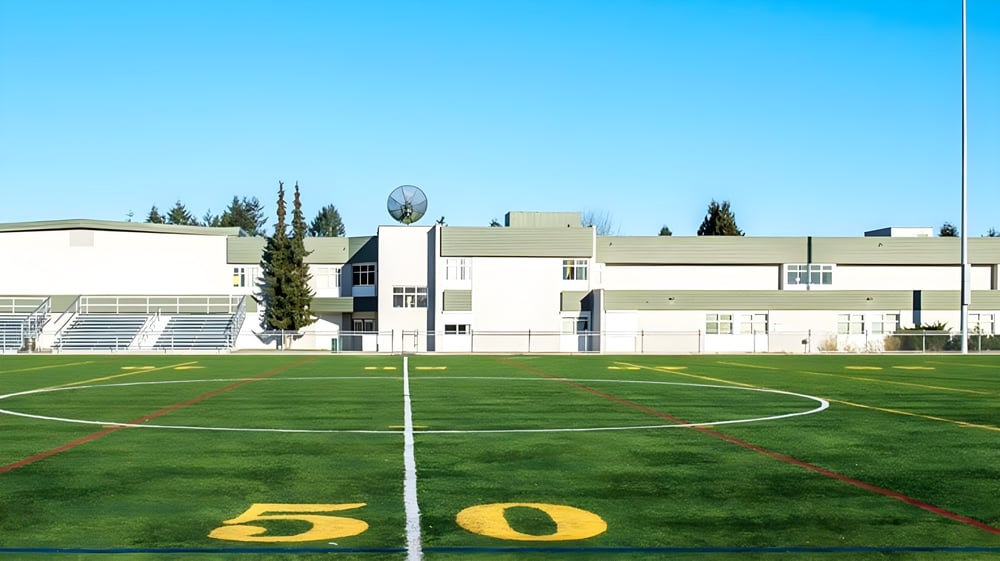 Das Soccer-Feld der Pitt Meadows Secondary School mit einer 50-Yard-Linie und einer Stadionstruktur im Hintergrund.