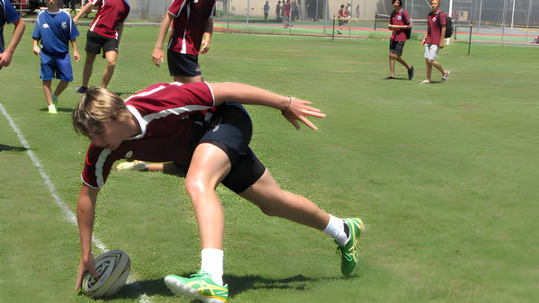 Eine Fußballspielerin der Pittwater High School taucht auf dem Spielfeld, um den Ball zu erreichen.