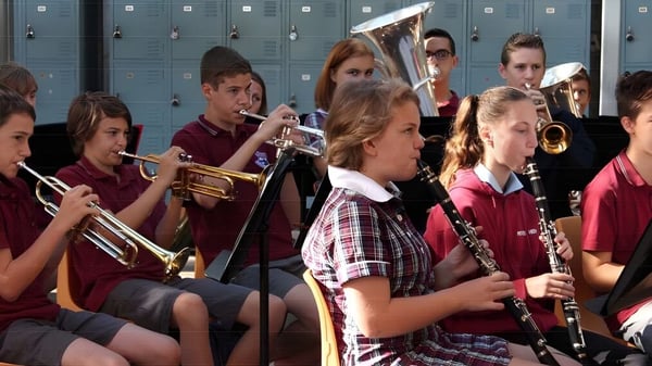Schüler der Pittwater High School stehen mit Musikinstrumenten im Schulflur vor den Schließfächern.