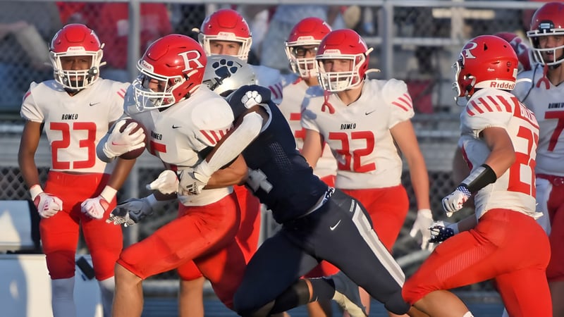 Eine Gruppe von Fußballspielern in roten Trikots steht auf dem Spielfeld mit einem Trainer auf dem Campus der Plaza Heights Christian Academy.