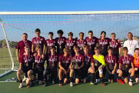 Eine Gruppe von Schülerinnen und Schülern der Plaza Heights Christian Academy posiert gemeinsam auf dem Fußballfeld vor dem Tor.