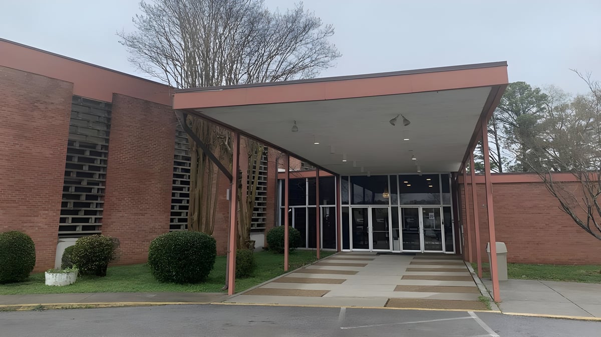 Das Backsteingebäude mit überdachtem Eingangsbereich der Plaza Heights Christian Academy ist von Bäumen und einem gepflasterten Weg umgeben.