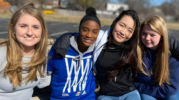 Vier Schülerinnen der Plaza Heights Christian Academy stehen an einem sonnigen Tag draußen zusammen.