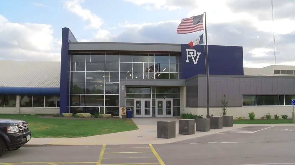 Das große blau-weiße Gebäude der Pleasant Valley High School mit dem Schriftzug RV und einer amerikanischen Flagge im Außenbereich.