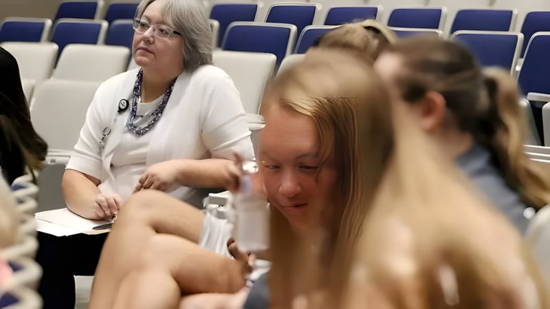 Zwei Frauen sitzen im Konferenzraum der Pleasant Valley Secondary School vor Reihen blauer Sitze.