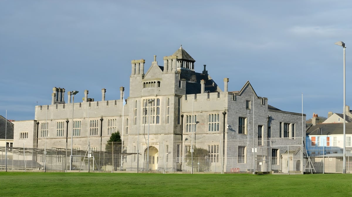 Ein mittelalterlich gestaltetes Schloss mit Türmen steht auf dem Gelände des Plymouth College vor einer Grasfläche.