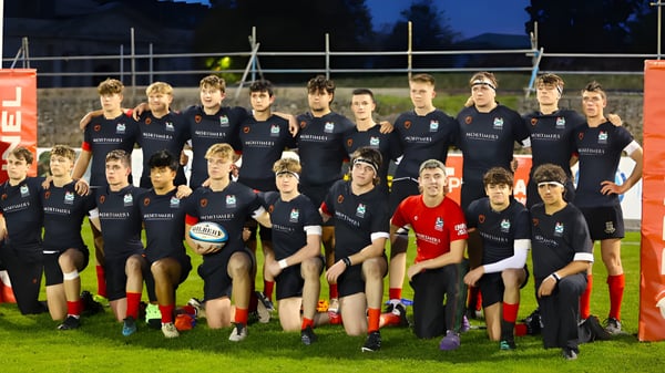 Eine Gruppe junger Athleten steht im einheitlichen Dress auf dem Sportplatz des Plymouth College bei Nacht unter Flutlicht.