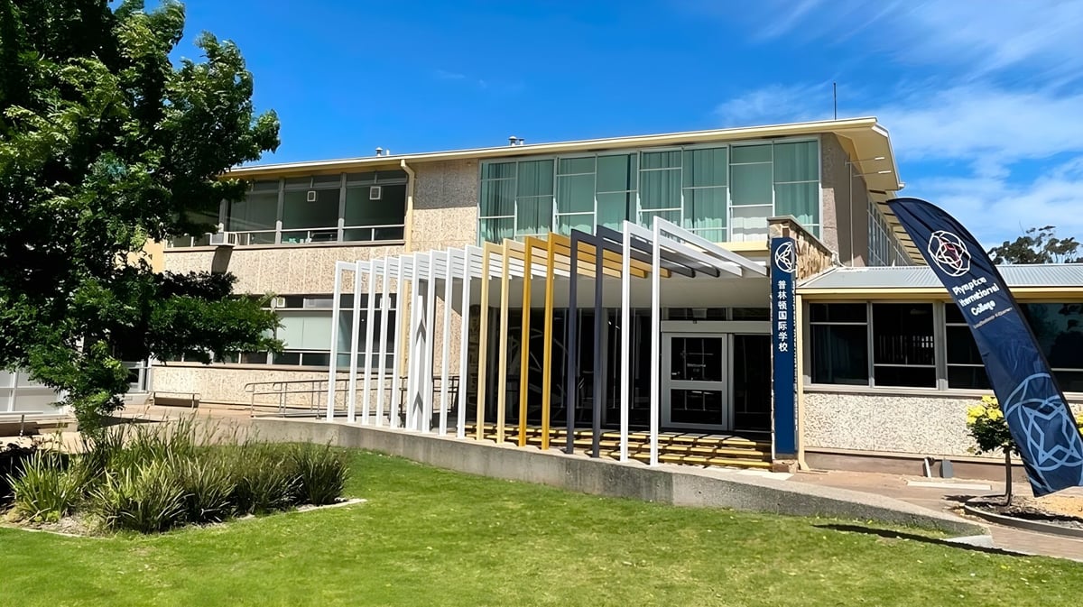 Das moderne mehrstöckige Gebäude mit Glasfassade und Grünfläche auf dem Campus des Plympton International College.