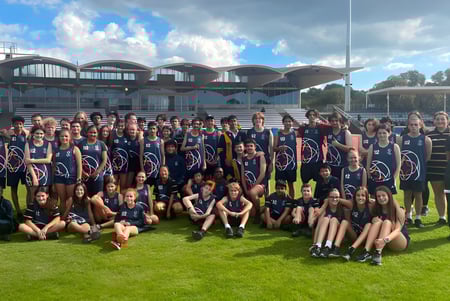 Eine Gruppe Schüler des Plympton International College posiert vor einem modernen, kuppelartigen Gebäude mit einem Grünfeld im Hintergrund.