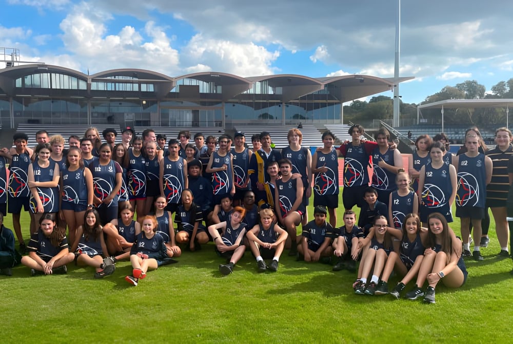 Eine Gruppe Schüler des Plympton International College posiert vor einem modernen, kuppelartigen Gebäude mit einem Grünfeld im Hintergrund.