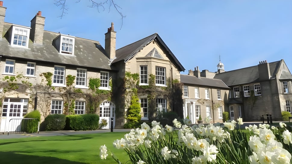Der Innenhof der Pocklington School zeigt einen gepflegten grünen Rasen und historische Steingebäude mit weißen Narzissen im Vordergrund.