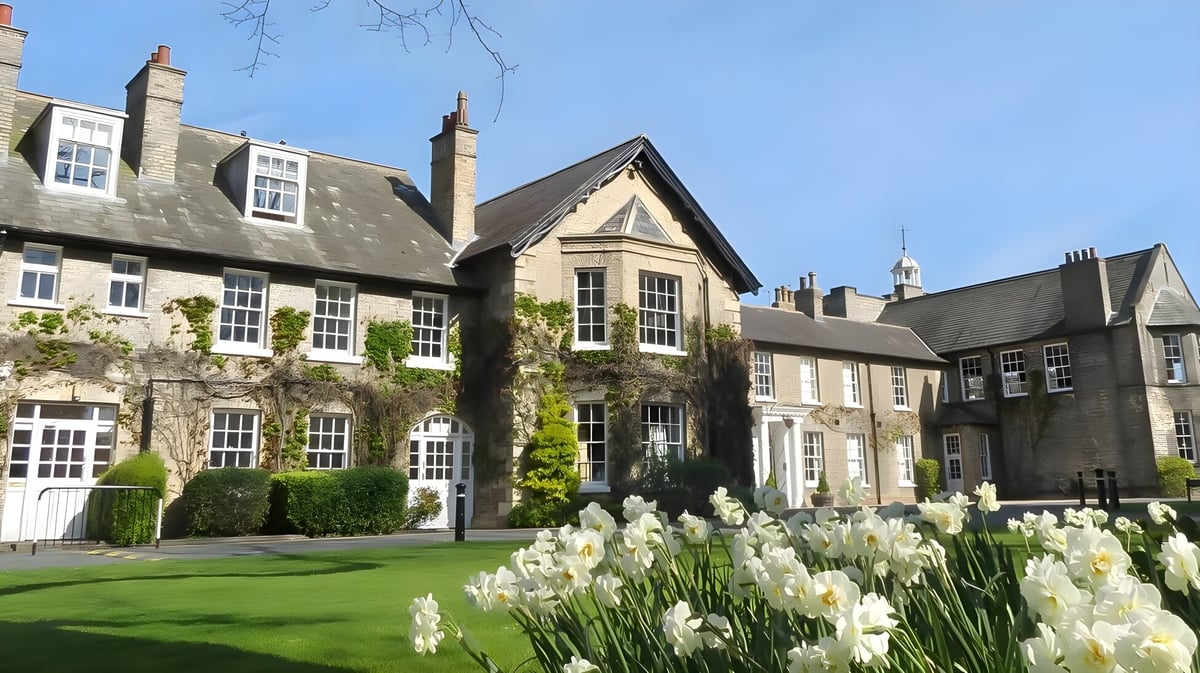 Der Innenhof der Pocklington School zeigt einen gepflegten grünen Rasen und historische Steingebäude mit weißen Narzissen im Vordergrund.