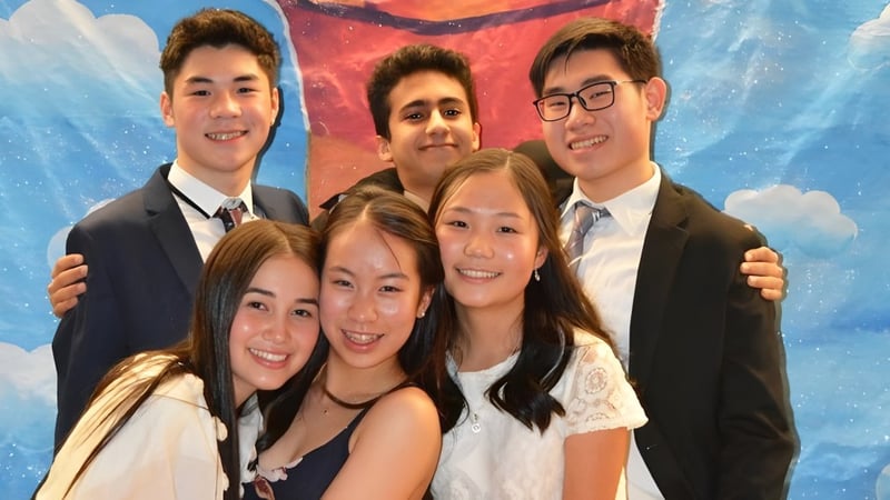 Eine Gruppe von Schülerinnen und Schülern der Point Grey Secondary School posiert vor einem bunten Hintergrund mit Wolken.