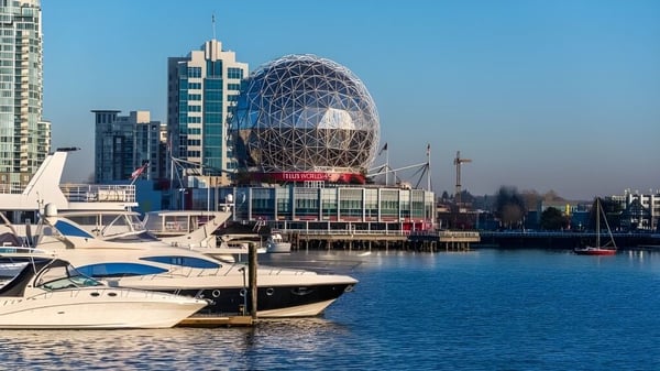 Das moderne Gebäude der Polyvalente Alexandre-J.-Savoie mit einer markanten Kuppel steht am Hafen mit mehreren Booten im Vordergrund.