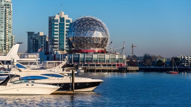 Das moderne Gebäude der Polyvalente Alexandre-J.-Savoie mit einer markanten Kuppel steht am Hafen mit mehreren Booten im Vordergrund.