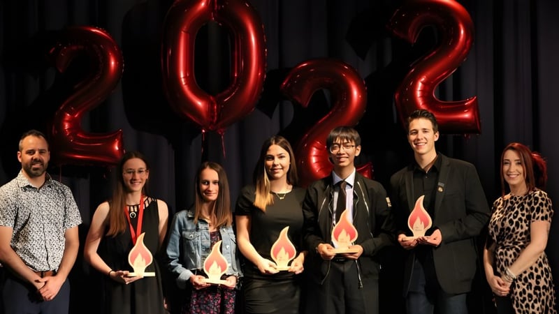 Eine Gruppe von Schülern posiert vor großen roten 2022-Ballons auf dem Campus der Polyvalente Alexandre-J.-Savoie.