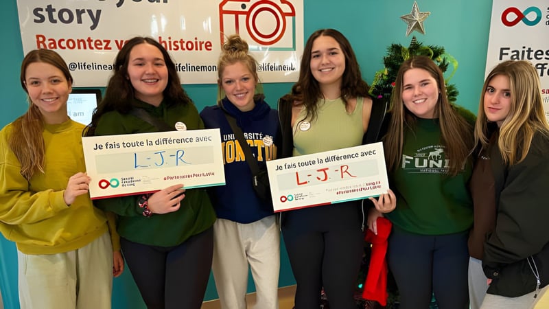 Eine Gruppe Schülerinnen hält Schilder mit den Buchstaben LJR in einem Klassenraum der Polyvalente Louis-J.-Robichaud.
