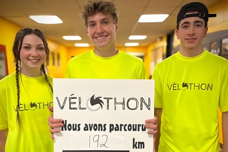 Drei Schülerinnen und Schüler der Polyvalente Louis-J.-Robichaud tragen gelbe VELOTHON-Shirts und halten ein Schild mit der Aufschrift 192 km.