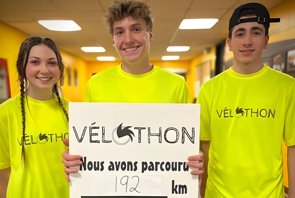 Drei Schülerinnen und Schüler der Polyvalente Louis-J.-Robichaud tragen gelbe VELOTHON-Shirts und halten ein Schild mit der Aufschrift 192 km.
