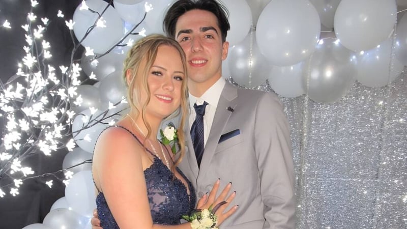 Ein Paar in festlicher Kleidung posiert gemeinsam vor funkelnden Lichtern auf einer Feier der Polyvalente Louis-Mailloux.